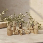 Olive wood nativity set displayed on table with olive branches as Christmas religious gift and home altar centerpiece