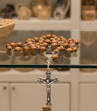 Close-up detail of hand-polished oval olive wood rosary beads with silver-tone metal links