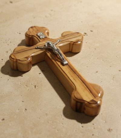 Close-up detail of hand-polished wooden crucifix showing olive wood grain and silver corpus